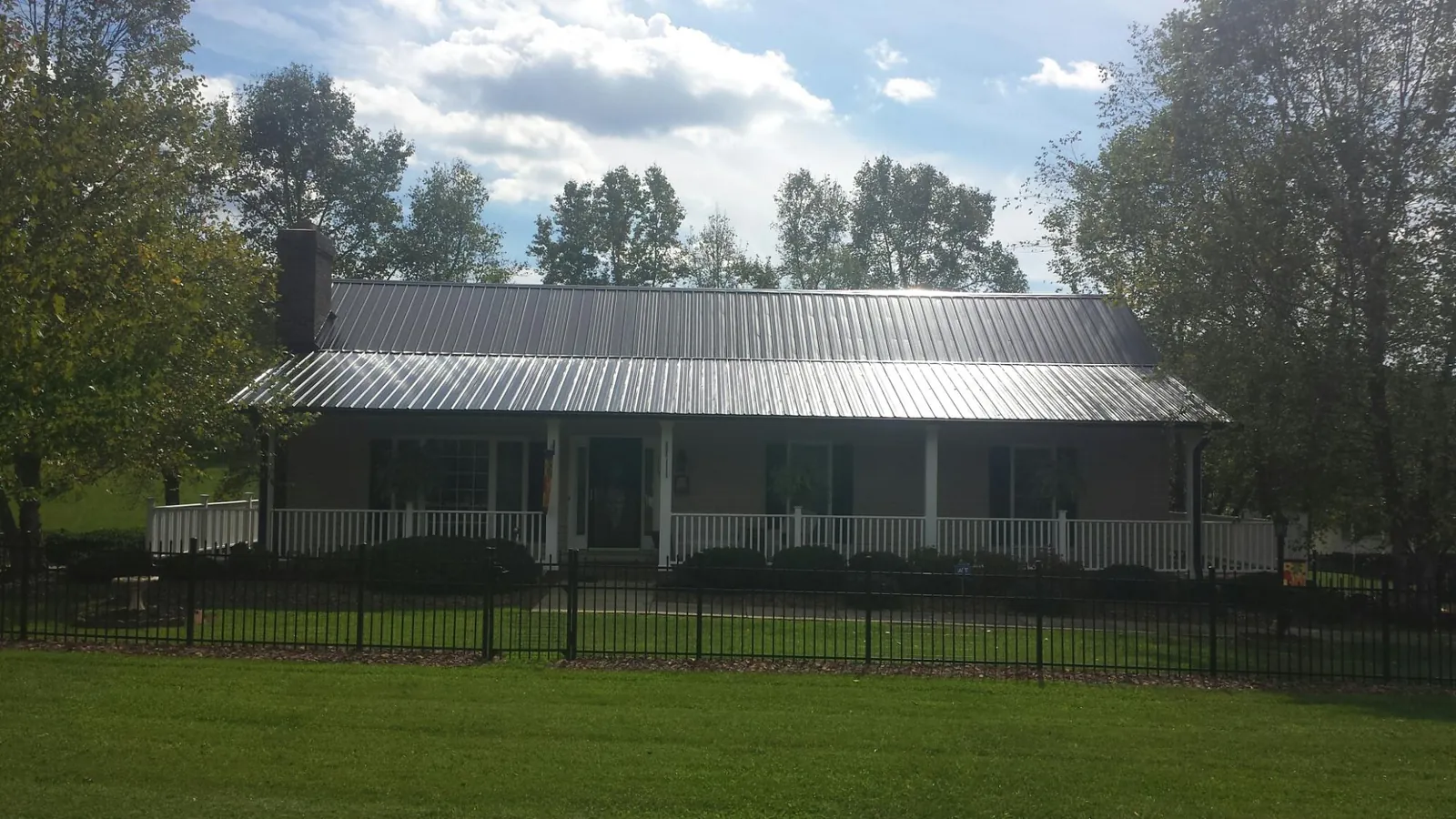 Gray metal roof on a brick ranch with a full width front porch — Gutter Guard Installation work by our crew in Farmington