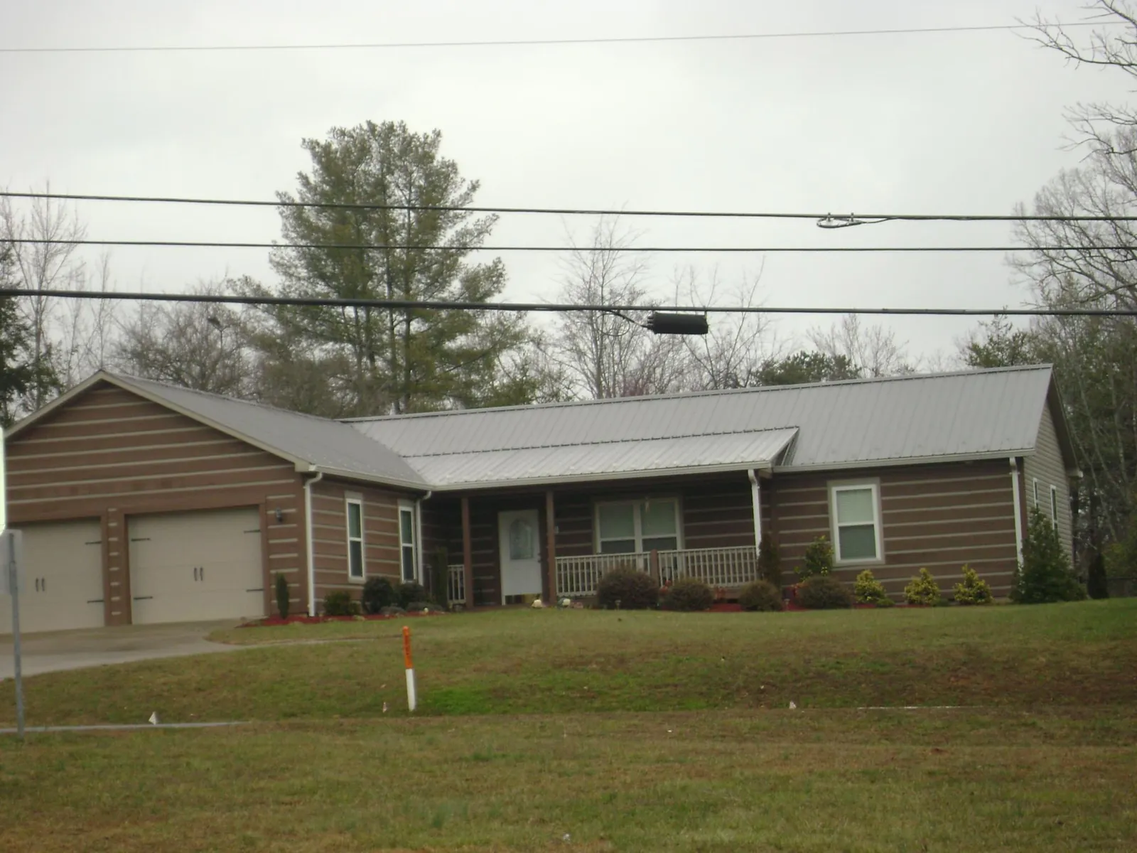 Gray metal roof on a log sided ranch home with a front porch in Farmington
